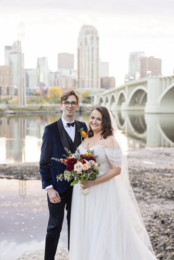 bride and groom portrait with Minneapolis skyline and river in background