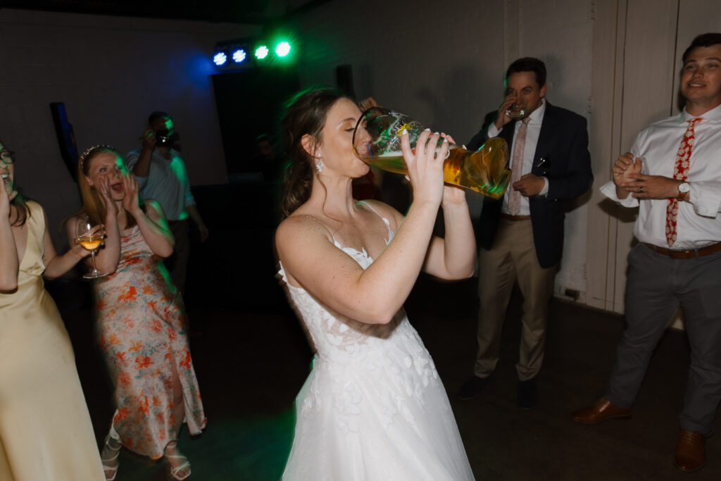Bride dancing and drinking from a bottle at the wedding reception.