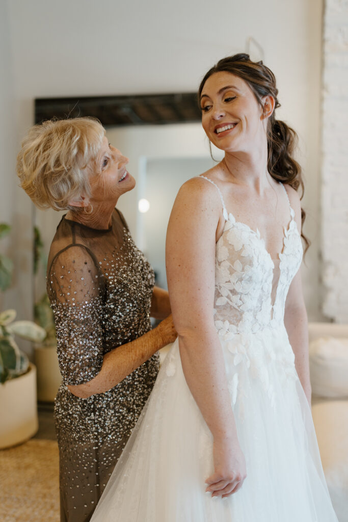 Mother and bride sharing a joyful moment, both smiling.