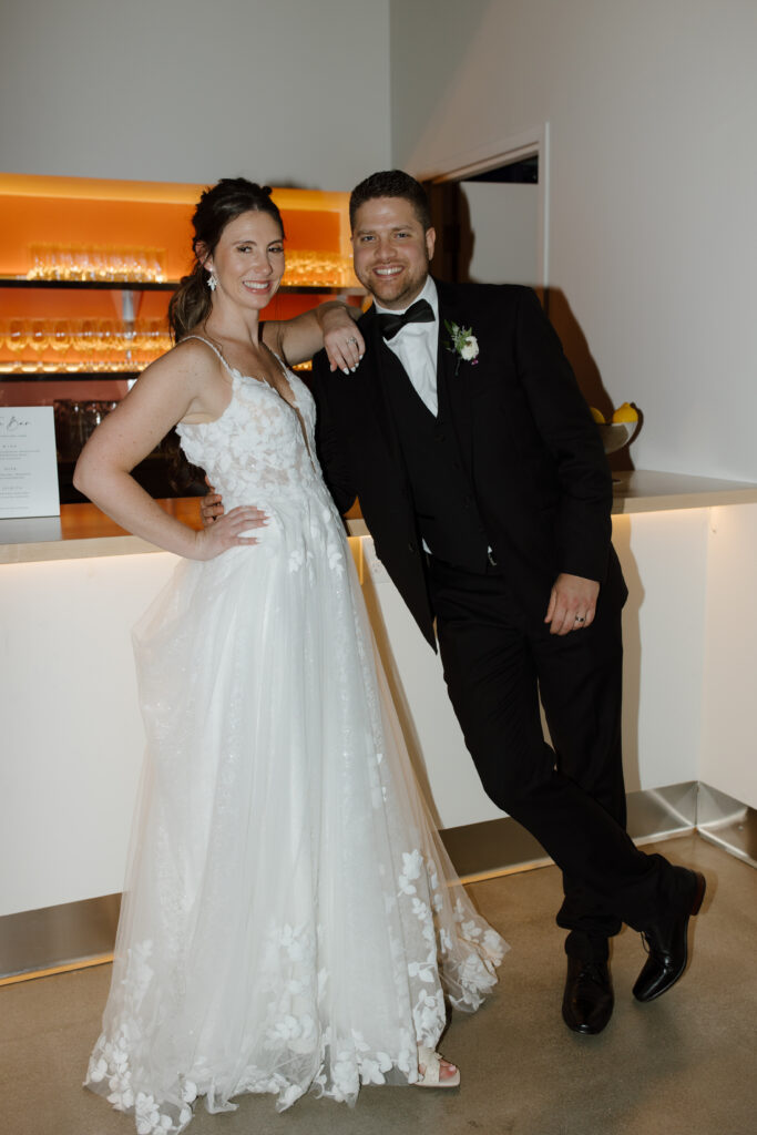 Bride and groom posing at the bar during their reception.