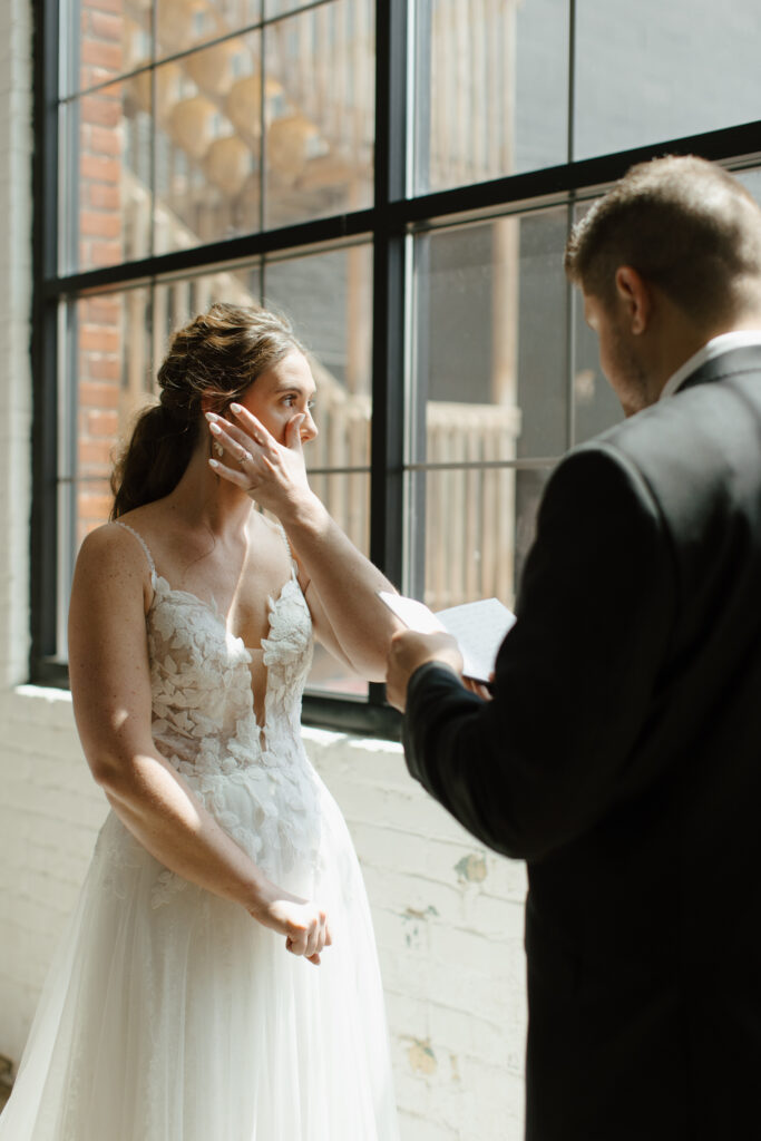 Tender moment as groom wipes a tear from the bride's face during the wedding.