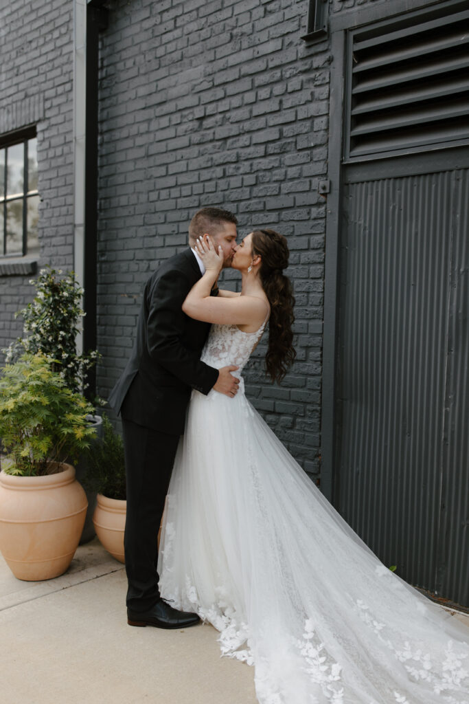 Bride and groom embracing in a modern, industrial-style outdoor setting.
