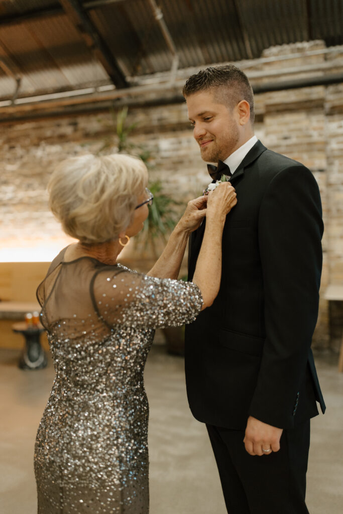 Mother of the groom adjusting his boutonniere before the ceremony.