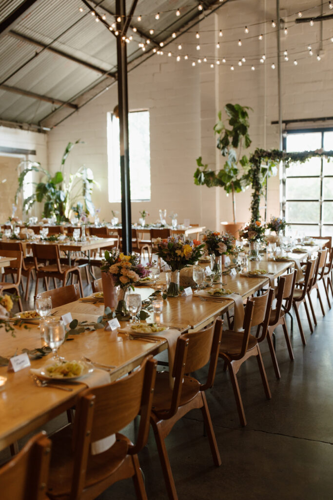 Wedding reception venue with long wooden tables decorated with greenery and candles