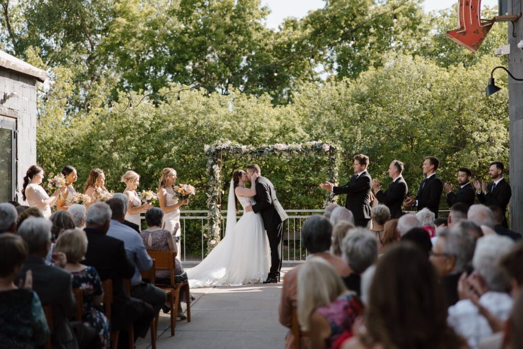 Outdoor wedding ceremony with bride and groom at the altar, guests seated.