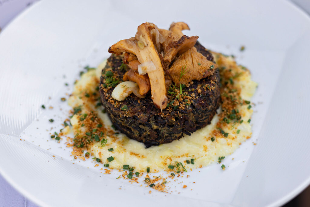 Hearty vegetarian entrée topped with roasted mushrooms, served over mashed potatoes with herbs and crispy garnish.